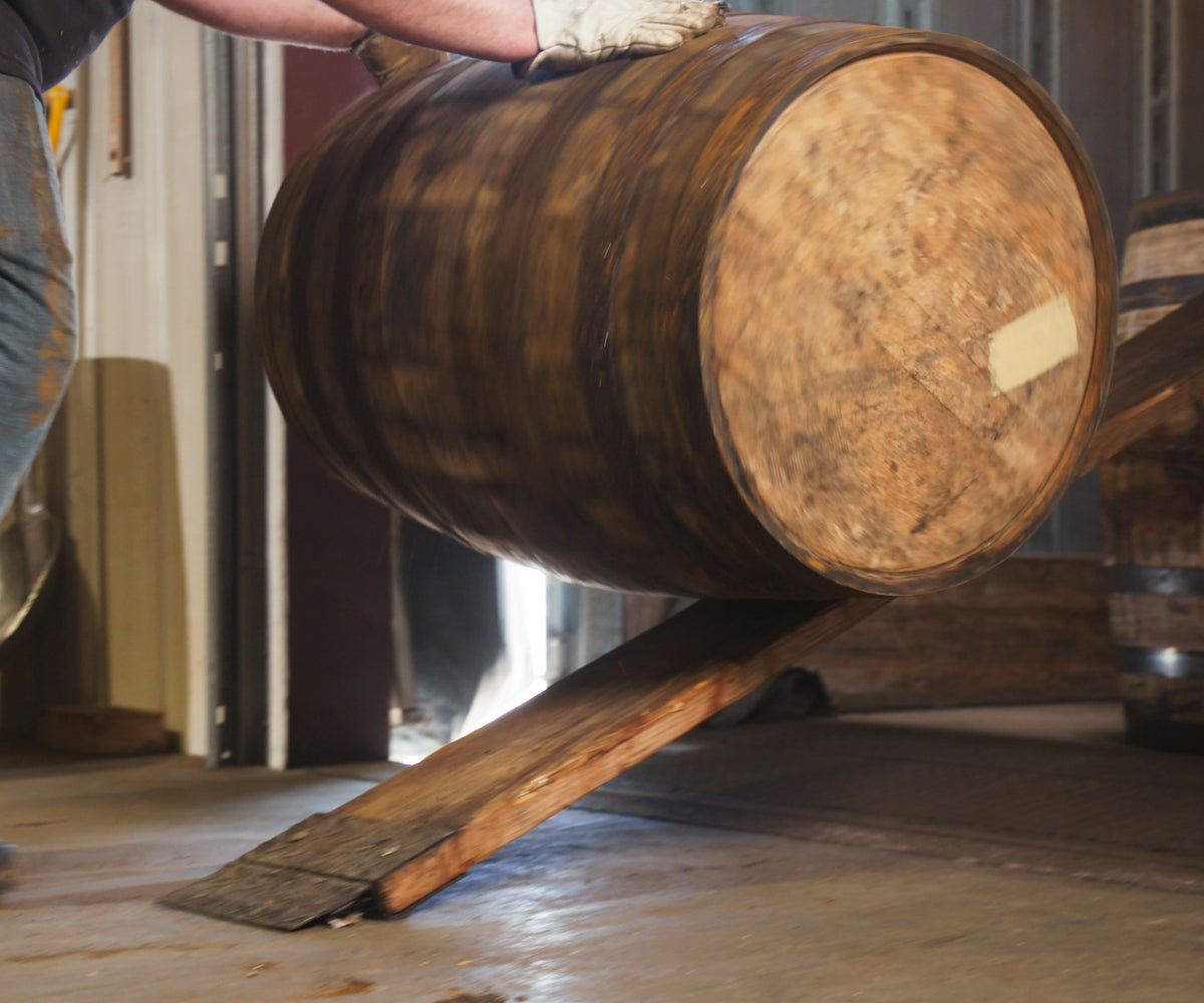Whiskey barrel being pushed up ramp onto truck