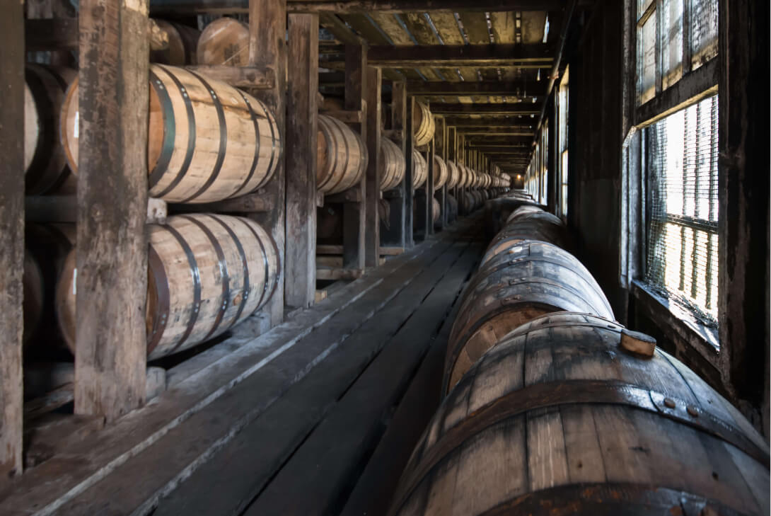 Barrel warehouse full of bourbon barrels, whiskey barrels, and whisky barrels aging to produce bourbon and whiskey.