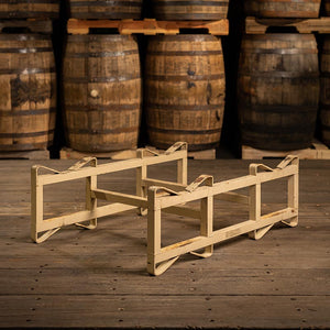 
                  
                    Used steel barrel rack with two single bars across in front of used bourbon barrels stacked on pallets
                  
                