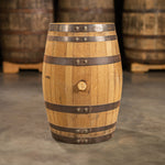 Side of a 15 Gallon Wood Hat Whiskey Barrel with other used whiskey barrels on pallets in the background