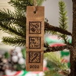 Wine barrel stave engraved ornament with three squares, one with a mitten and heart drawing, a second with ho ho ho, and a third with a candy cane and 2022 at the bottom