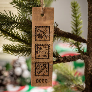 
                  
                    Wine barrel stave engraved ornament with three squares, one with a mitten and heart drawing, a second with ho ho ho, and a third with a candy cane and 2022 at the bottom
                  
                