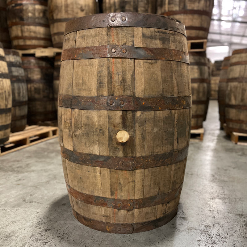 
                  
                    Side and bung of a 10 Year Henry McKenna Bourbon Barrel with other used bourbon barrels stacked on pallets in the background
                  
                