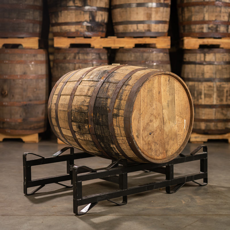 A Templeton 10 Year Reserve Rye Whiskey Barrel laying on a barrel rack with barrels stacked on pallets in the background