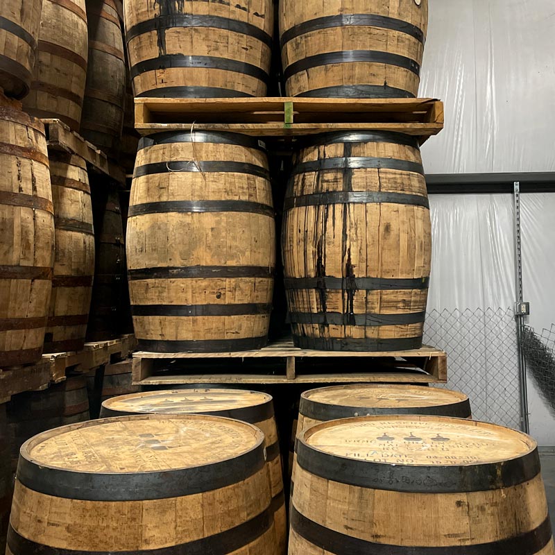 
                  
                    Woodford Reserve Kentucky Straight Malt Whiskey barrels stacked on pallets in warehouse
                  
                