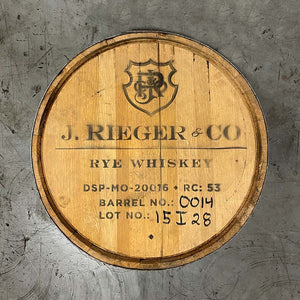 
                  
                    Head of a J Rieger and Co Rieger's Rye Whiskey barrel with shield logo and distillery markings
                  
                