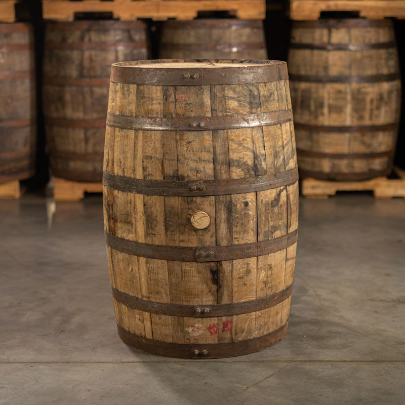 Side of a used 1792 High Rye Bourbon Barrel with other barrels stacked on pallets in the background