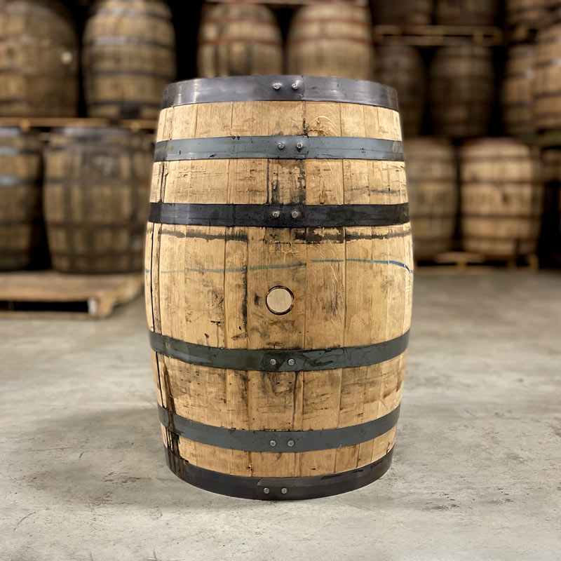 
                  
                    Side of a Woodford Reserve Double Oaked Bourbon barrel with other used bourbon barrels stacked on pallets in the background
                  
                