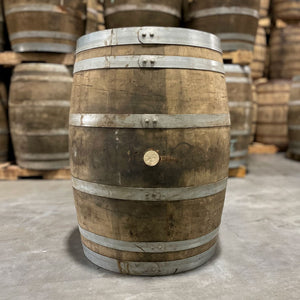 
                  
                    Side of a Jim Beam Wine Cask Finished Bourbon Barrel with other used wine barrels stacked on pallets in the background
                  
                