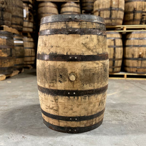 
                  
                    Side of a Lucky Seven Bourbon Holiday Toast Barrel with other used bourbon barrels stacked on pallets in the background
                  
                