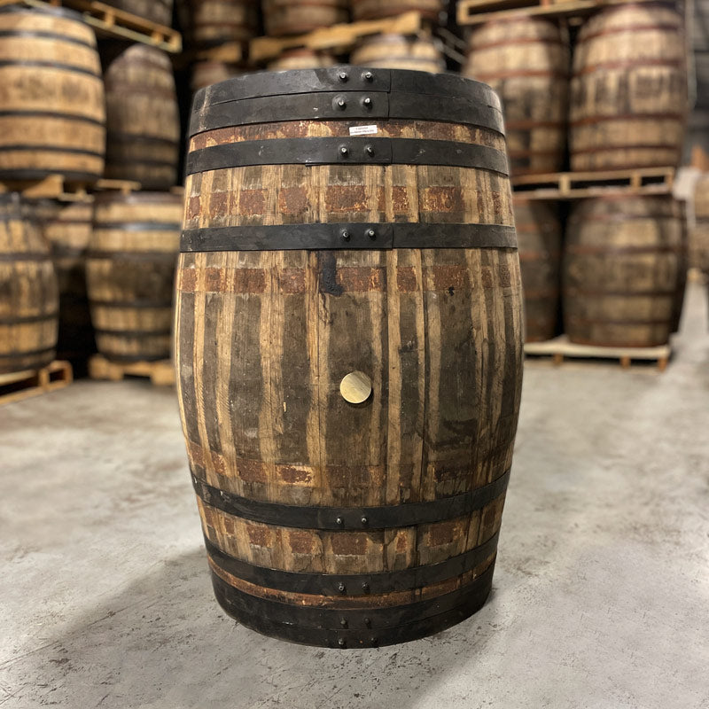 Side with bunghole of an Old Elk Oloroso Sherry Cask Finish Bourbon Barrel and other used barrels on pallets in the background