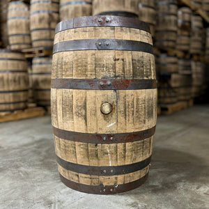 
                  
                    Side of a 2 year Heaven Hill bourbon barrel with other used bourbon barrels stacked on pallets in the background
                  
                