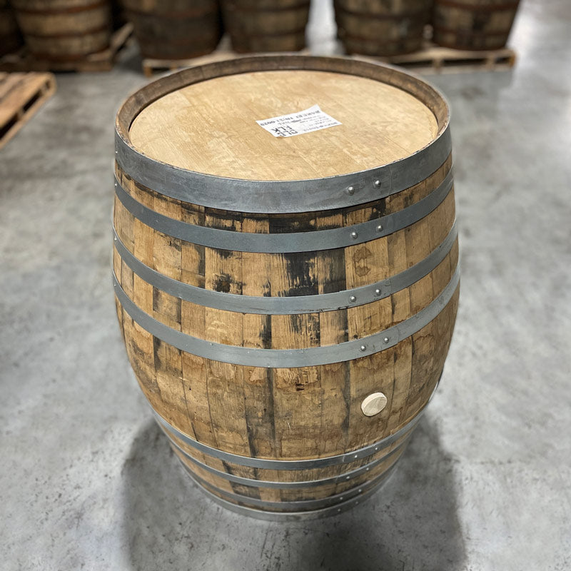 Head and bung hole side of an Old Elk Armagnac Cask Finished Bourbon Barrel with other used barrels in the background