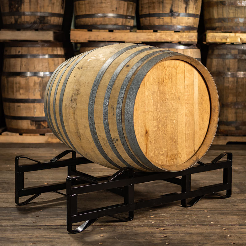 220 liter Oloroso sherry cask on a rack with barrels stacked on pallets in the background