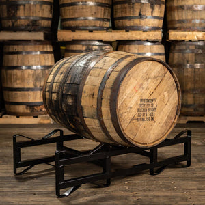 
                  
                    4 year age statement Wild Turkey bourbon barrel on a rack with distillery markings on head and barrels stacked on pallets in the background
                  
                