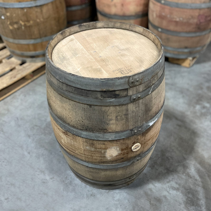 Head and side of a 225 liter Cognac Cask with other used cognac and port barrels on pallets in the background