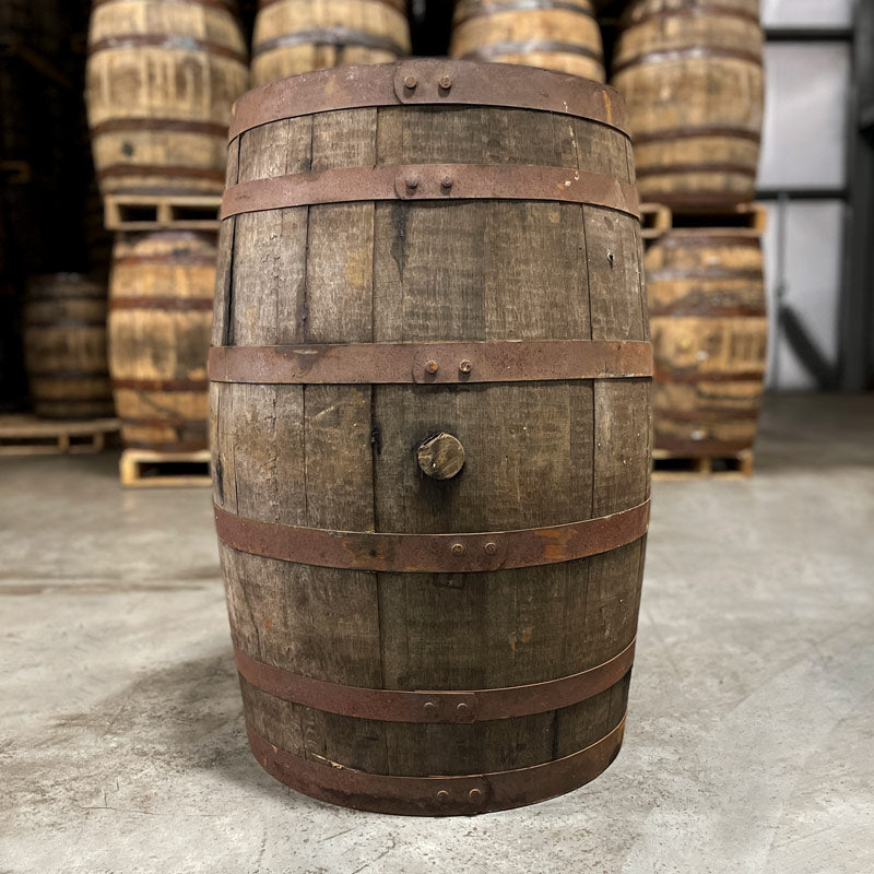 Side with belly bung of a Virgin Islands Rum Barrel and other used barrels stacked in the background