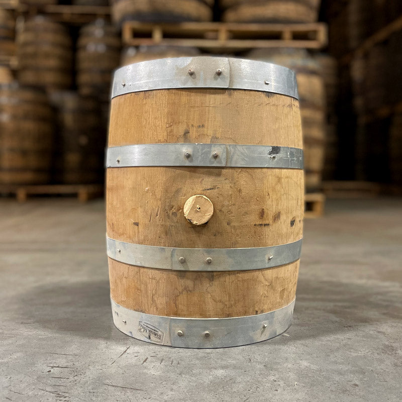 Side of a 5 gallon Lonely Oak Bourbon Barrel with other full size bourbon barrels in the background