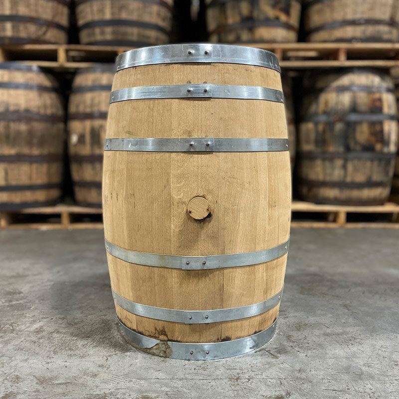 
                  
                    Side view with bung of a 30 Gallon Lonely Oak Bourbon Barrel with other used whiskey barrels on stacked on pallets in the background
                  
                