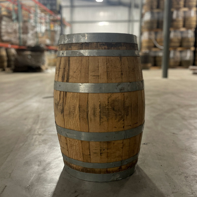 13 gallon John Emerald Distilling gin barrel side view with stacks of barrels on pallets in background