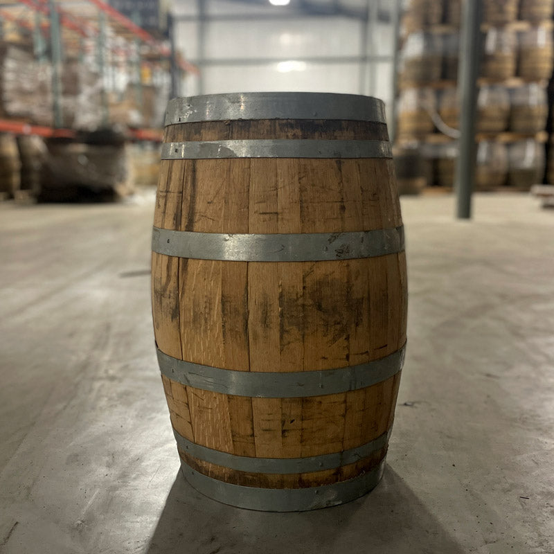 
                  
                    13 gallon John Emerald Distilling gin barrel side view with stacks of barrels on pallets in background
                  
                