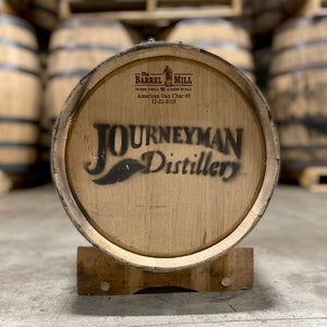
                  
                    Other end of a Journeyman Distillery 5 gallon whiskey barrel on a stand and distillery name stamped on head.
                  
                