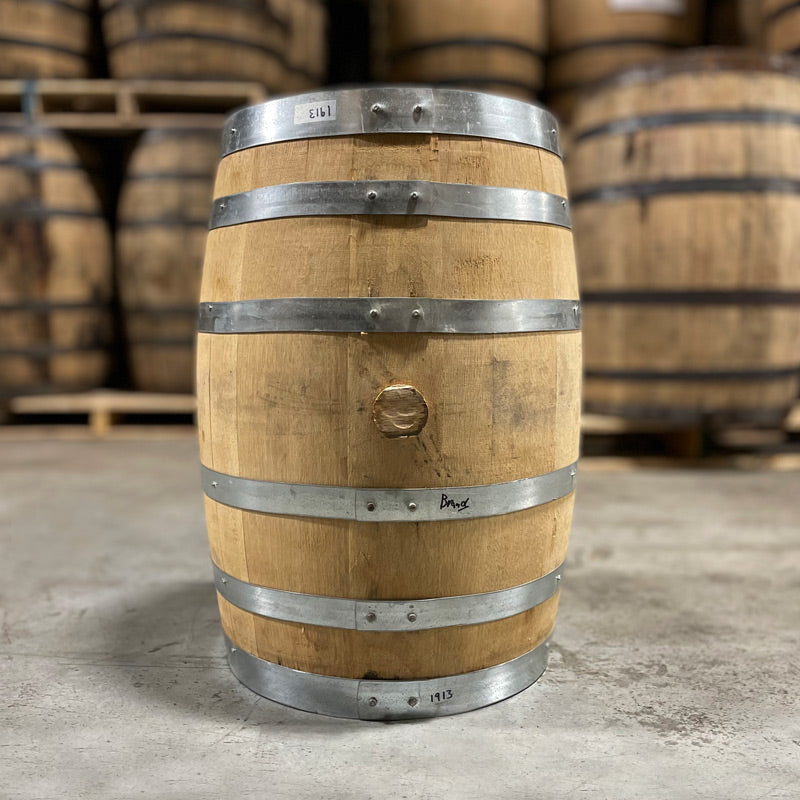 Side of a 15 Gallon Old Sugar Distillery Brandy Barrel with other used barrels stacked on pallets in the background