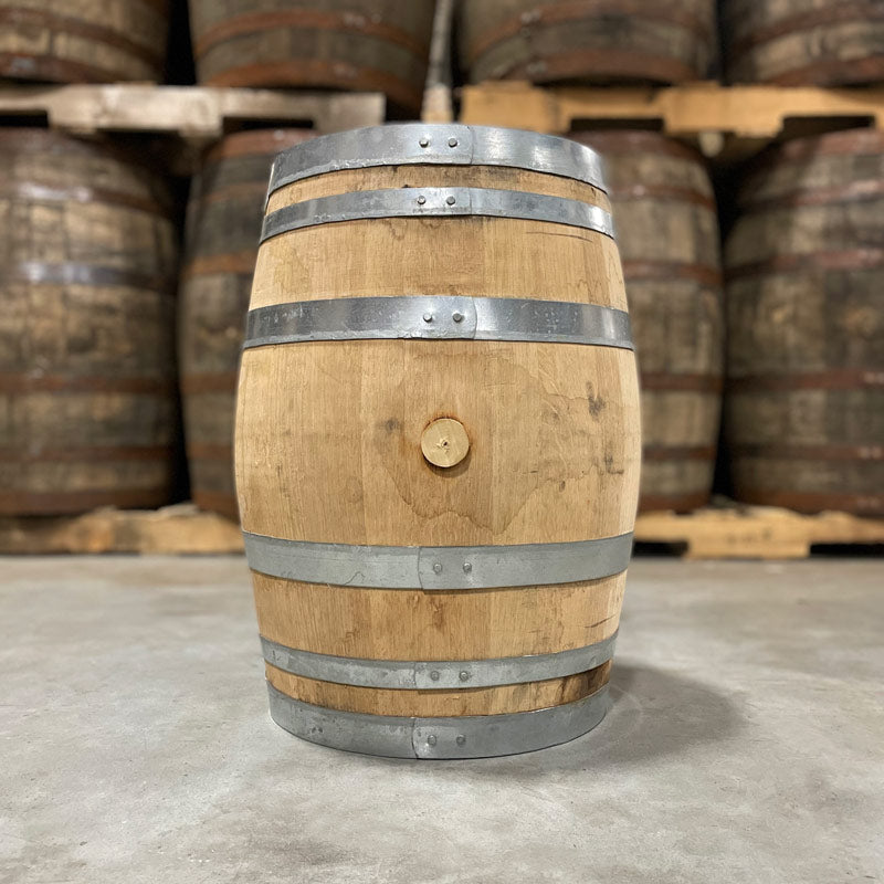 Side with bung of a 15 Gallon Rock Town Distillery Bourbon Barrel with other barrels on pallets in the background