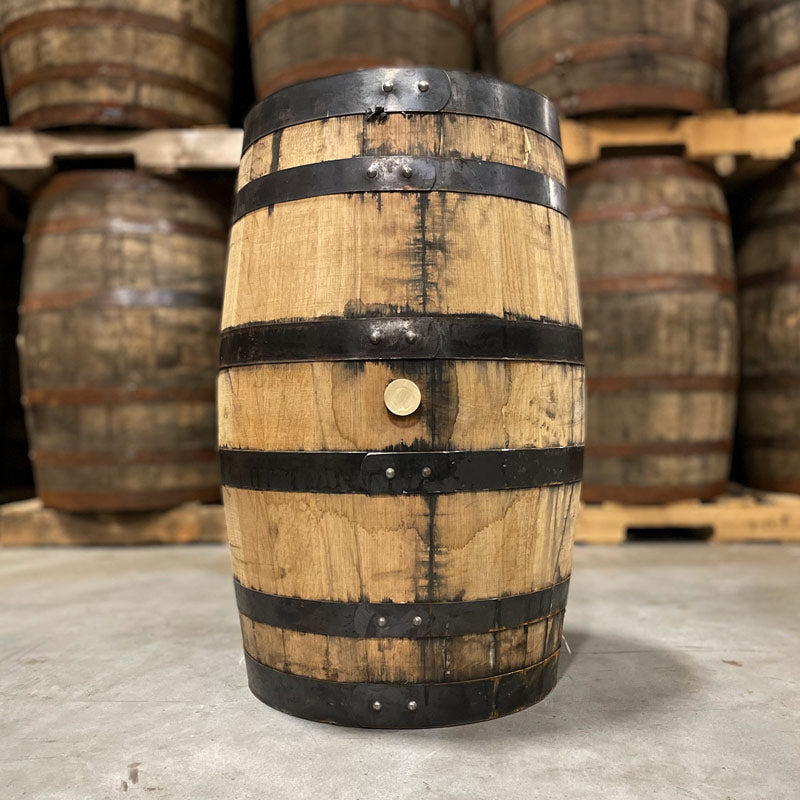 Side with bung of a 25 Gallon Rock Town Distillery Bourbon Barrel with other used barrels on pallets in the background