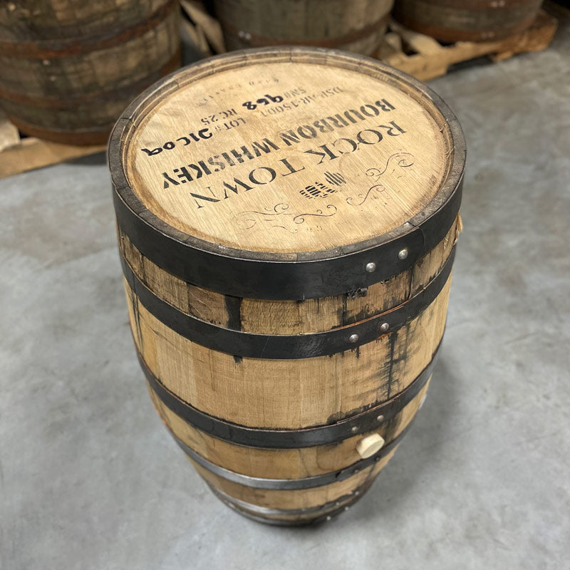 Side with bung and head of a 25 Gallon Rock Town Distillery Bourbon Whiskey Barrel with decorative barrel design, distillery information and barrel age on the head.