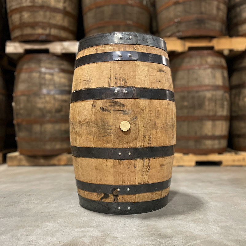 
                  
                    Side with bung of a 25 Gallon Rock Town Distillery Gin Barrel with other used barrels stacked on pallets in the background
                  
                
