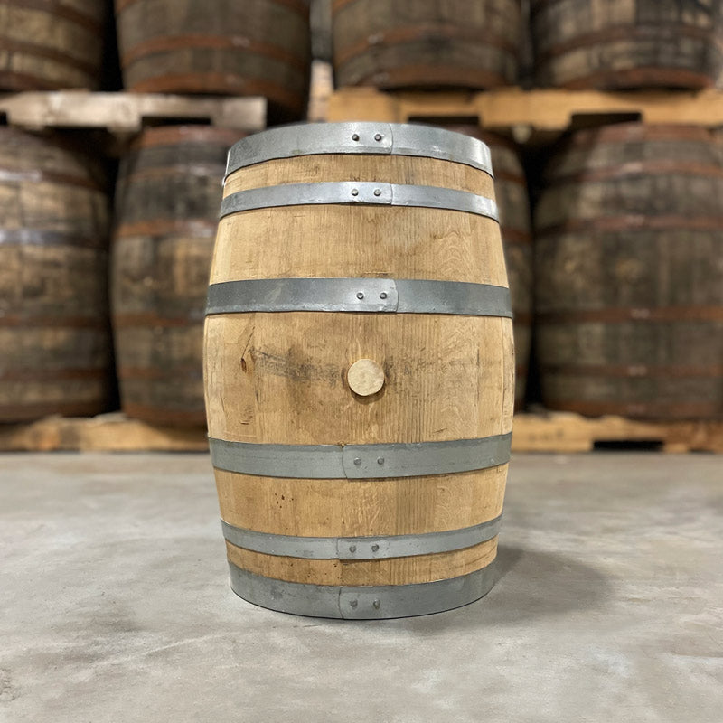 Side and bung of a 15 Gallon Rock Town Distillery Single Malt Whiskey Barrel with other used barrels on pallets in the background