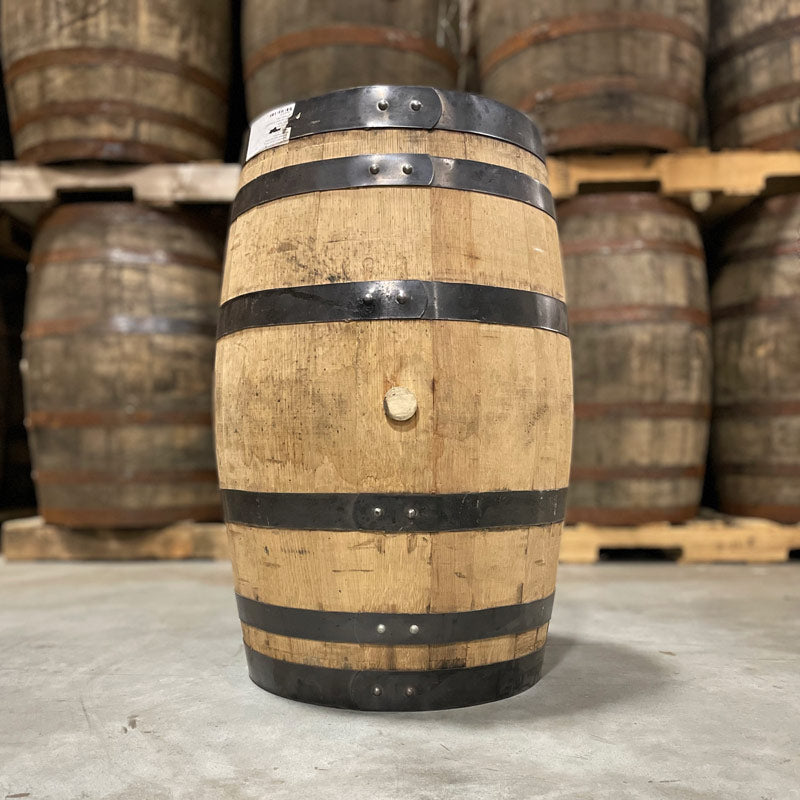 Side and bung of a 25 Gallon Rock Town Distillery Single Malt Whiskey Barrel with other used barrels on pallets in the background