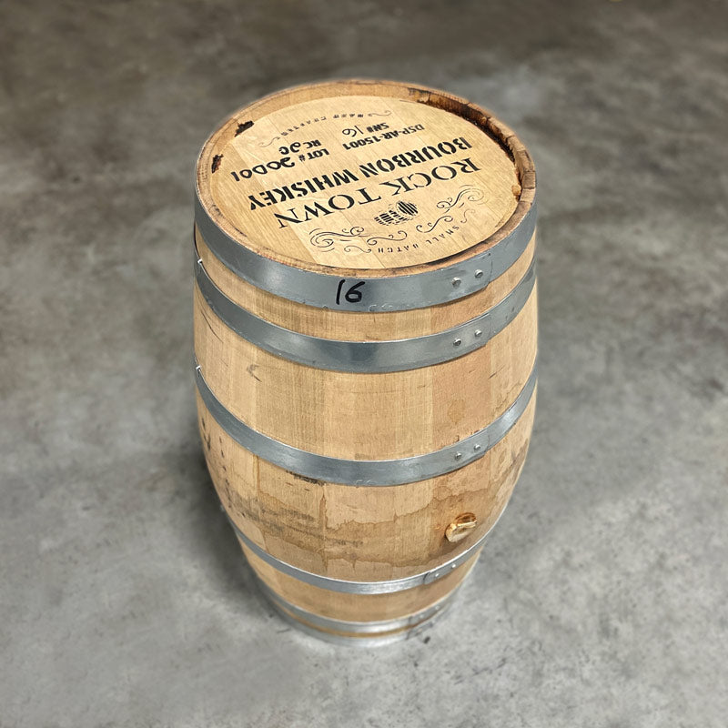 Head and side of a 20 Gallon Rock Town Bourbon Barrel with "Small Batch Rock Town Bourbon Whiskey Hand Crafted" and other distillery information stamped on the head with a barrel and decorative border on the top end of the head.