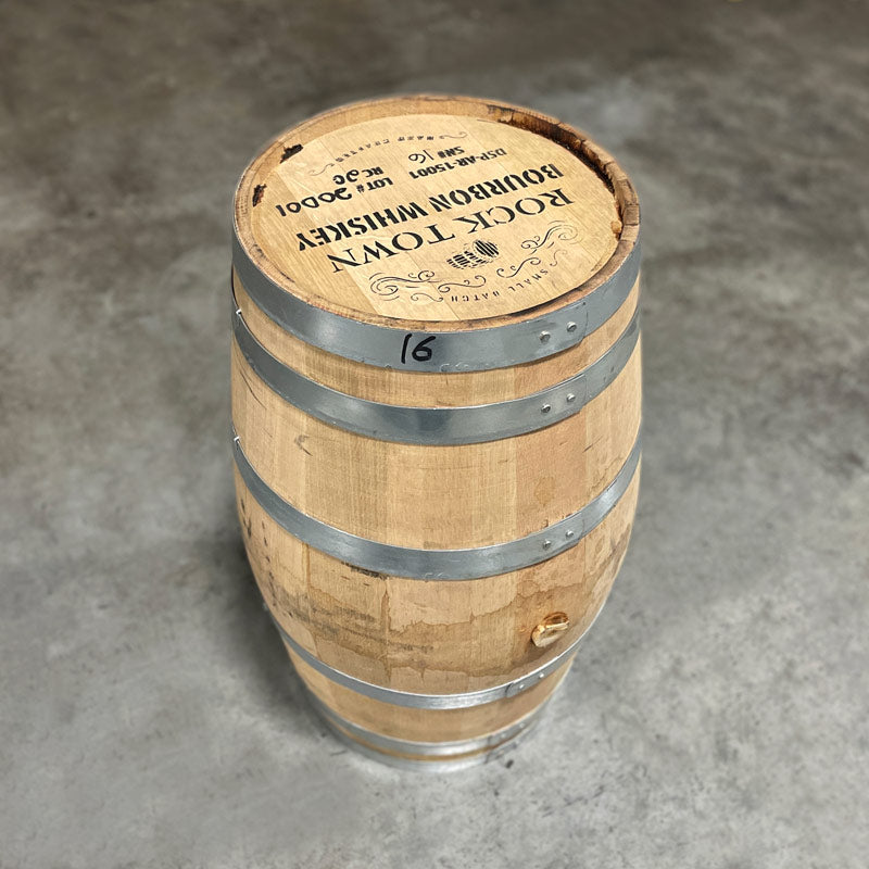 
                  
                    Head and side of a 20 Gallon Rock Town Bourbon Barrel with "Small Batch Rock Town Bourbon Whiskey Hand Crafted" and other distillery information stamped on the head with a barrel and decorative border on the top end of the head.
                  
                