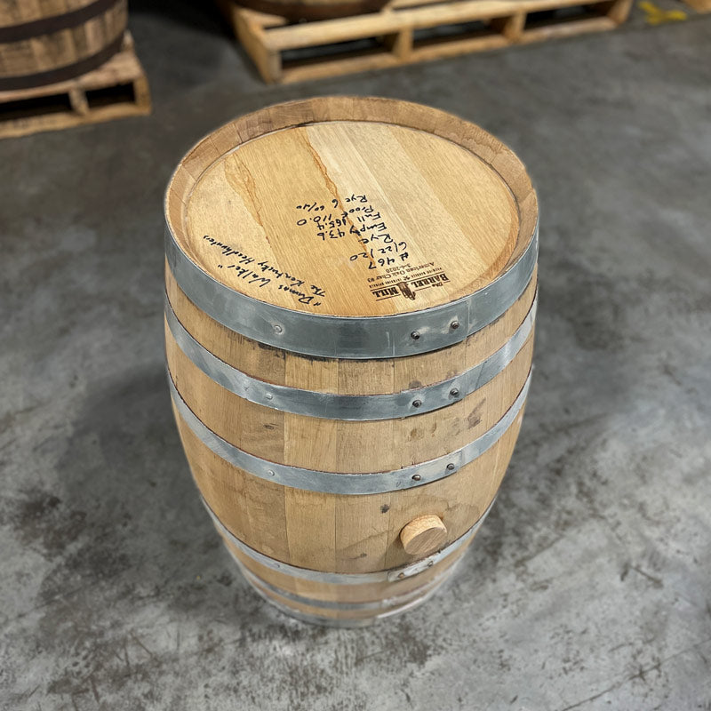 Head and side with bung of a 15 Gallon Lonely Oak Rye Whiskey Barrel with barrels on pallets in the background