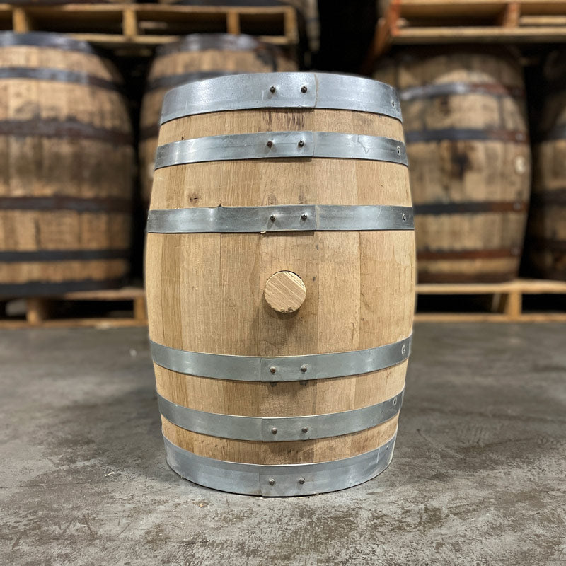 
                  
                    Side with bung of a 10 Gallon Lonely Oak Bourbon Barrel with used full-size bourbon barrels stacked on pallets in the background
                  
                