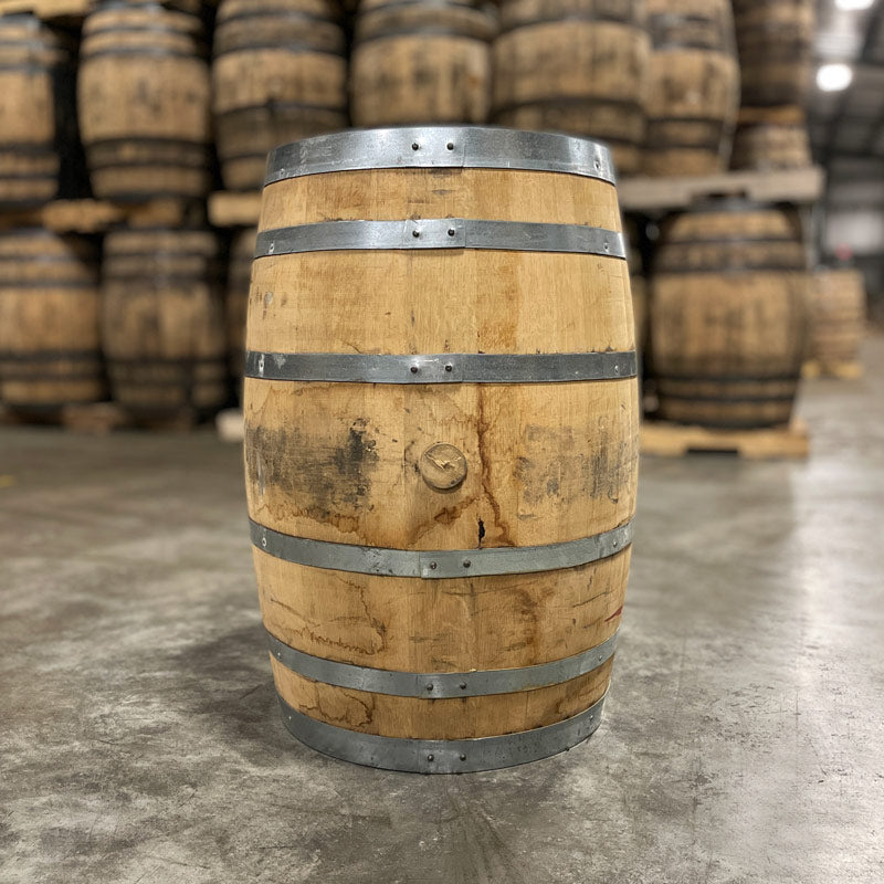 Side with bung of a 30 Gallon West Fork Rye Bourbon Barrel with other used barrels in the background