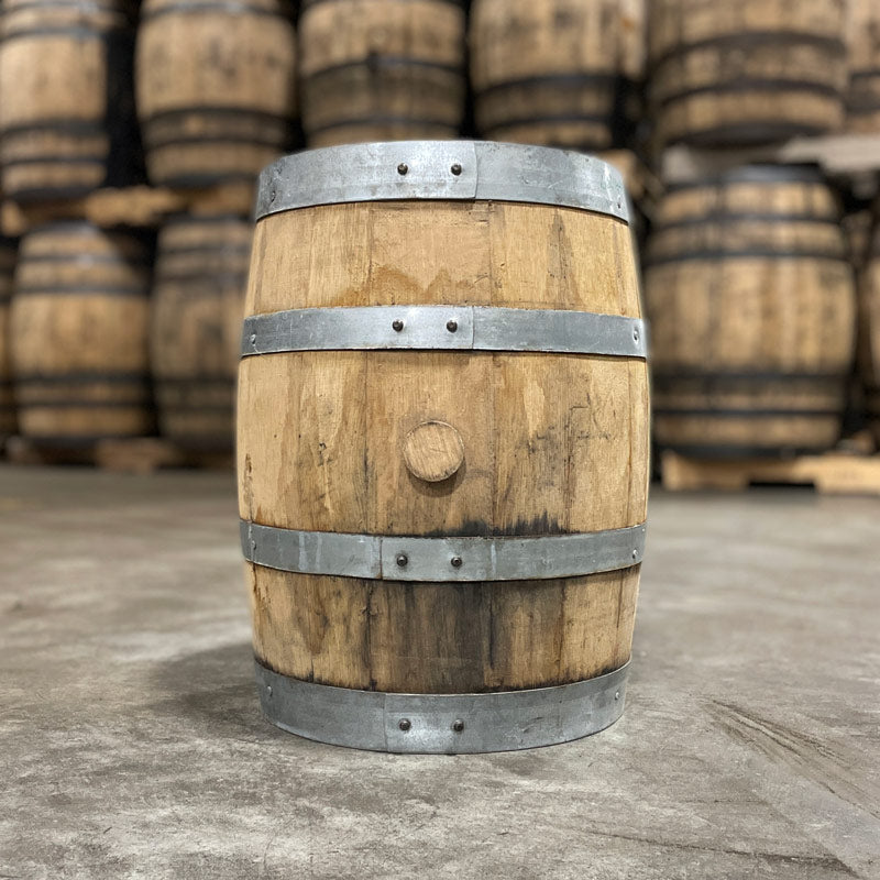 Side with bung of a 5 Gallon Journeyman Honey Barrel with other used barrels stacked in the background