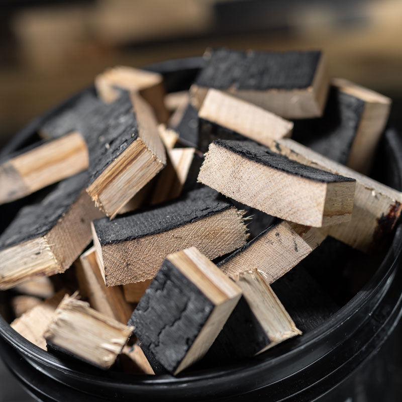 Close up view of the top of a filled Bourbon Barrel Smoking Wood Chunk Bucket with charred chunks inside