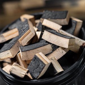 
                  
                    Close up view of the top of a filled Bourbon Barrel Smoking Wood Chunk Bucket with charred chunks inside
                  
                