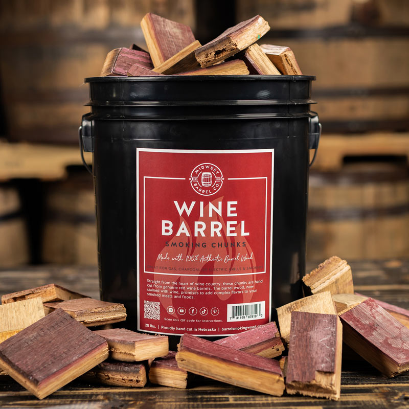 An overfilled bucket of Wine Barrel Smoking Wood Chunks with red wine stained staves and barrels stacked in the background
