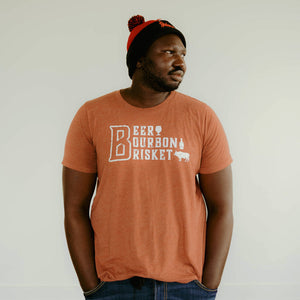 
                  
                    Man wearing burnt orange t-shirt with Beer Bourbon Brisket and beer glass, bourbon bottle and bull on front of the shirt
                  
                