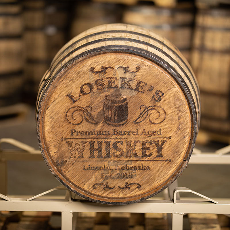 
                  
                    An engraved full size whiskey barrel with Loseke's Premium Barrel Aged Whiskey Lincoln, Nebraska Est. 2019 and barrel design engraved on head
                  
                