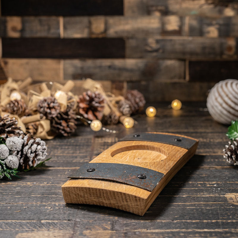 whiskey barrel stave candle holder with pine cones, Christmas lights and other holiday decorations nearby