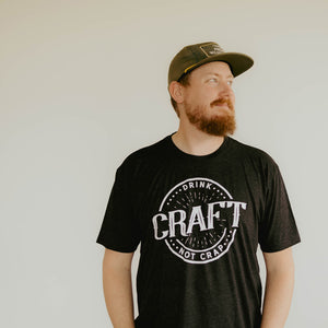 
                  
                    Man wearing charcoal gray t-shirt with circle design that says drink craft not crap
                  
                
