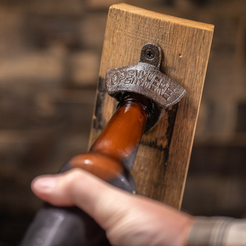 person using engraved stave bottle opener to open a beer bottle