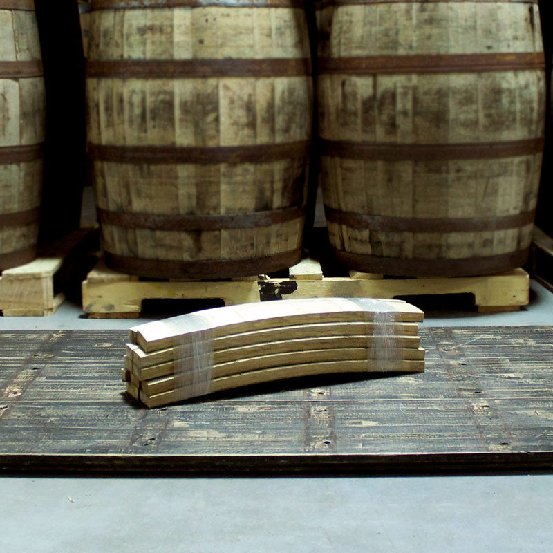 Plastic wrapped bundle of barrel stave firewood on floor in front of barrels on pallets