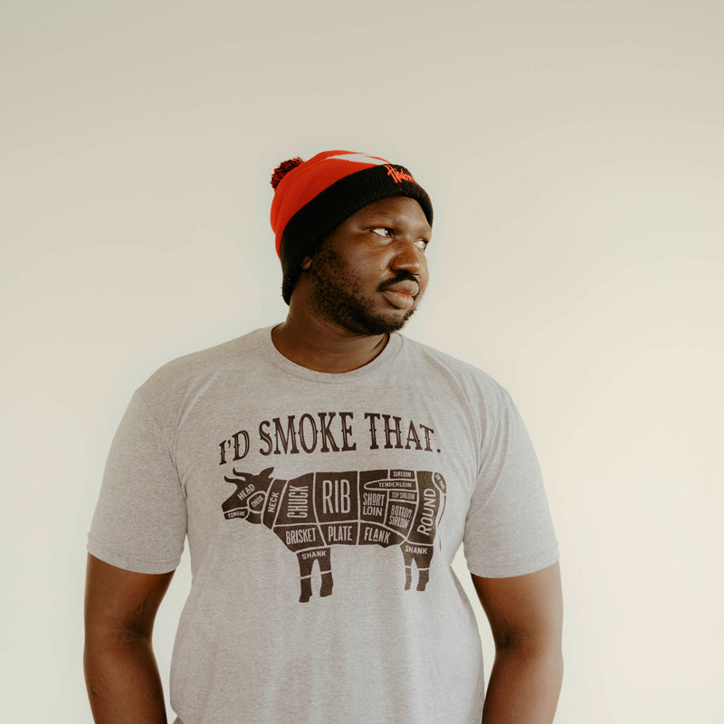 Man wearing light gray t-shirt with text I'd Smoke That above a bull with cuts of meat labeled on the bull 