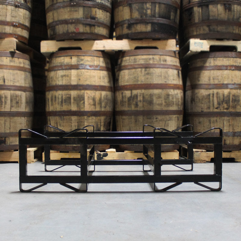 
                  
                    NEW 7", 2-Barrel, Double Bar Steel Rack (Black) on floor in front of barrels on pallets
                  
                